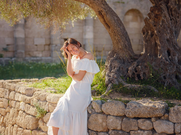 Schöne asiatische junge Frau in weißem Kleid draußen. Akropolis von Rhodos Berühmte Ruinen einer antiken Siedlung mit verschiedenen Gebäuden wie Stadion und Theater. - Foto, Bild