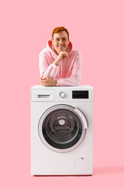 Young man near washing machine on pink background - Photo, Image