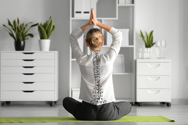 Młoda bizneswoman uprawiająca jogę w biurze. Pojęcie zdrowego kręgosłupa - Zdjęcie, obraz
