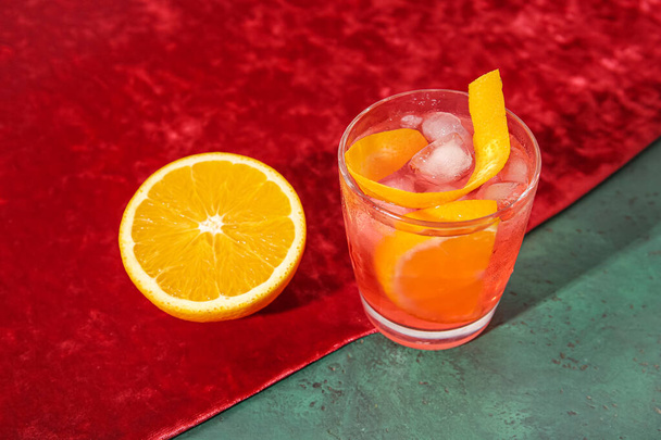 Glas koude Negroni cocktail en oranje en stof op tafel - Foto, afbeelding