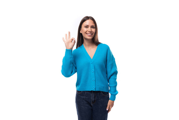 молода красива брюнетка, одягнена в синій V-подібний светр на білому тлі з копіювальним простором. - Фото, зображення