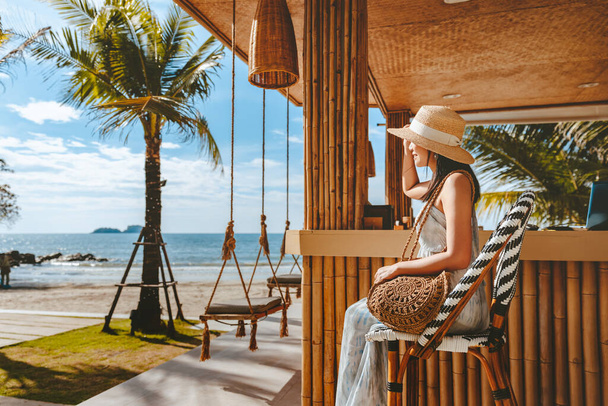 Viajes concepto de vacaciones de verano, Feliz viajero mujer asiática con sombrero y vestido relajarse en el columpio en la cafetería de la playa, Koh Chang, Tailandia - Foto, Imagen