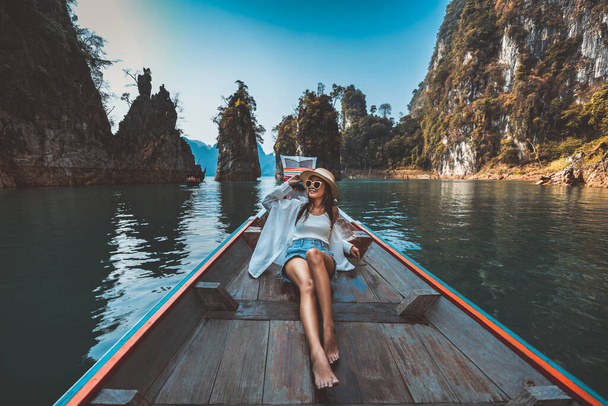 Travel summer holiday concept, Happy solo podróżnik azjatycka kobieta z kapeluszem relaks i zwiedzanie tajskiej łodzi longtail w Ratchaprapha Dam w Parku Narodowym Khao Sok, Prowincja Surat Thani, Tajlandia - Zdjęcie, obraz