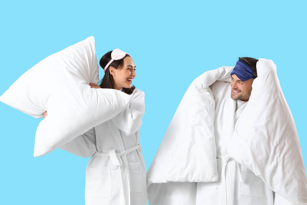 Молодая пара с подушкой и одеялом на голубом фоне - Фото, изображение