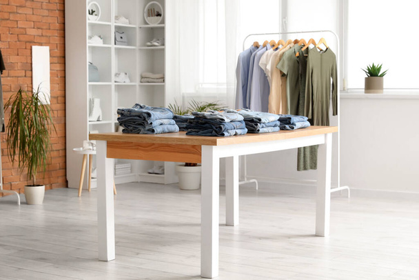 Table with stylish jeans pants in modern boutique - Photo, Image
