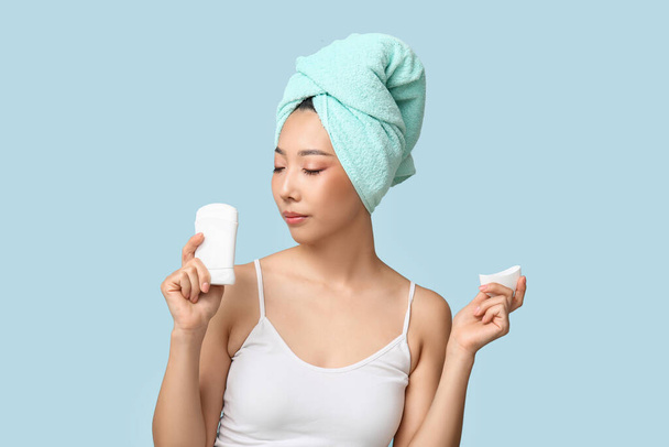 Mavi arka planda deodorantı olan genç Asyalı kadın. - Fotoğraf, Görsel