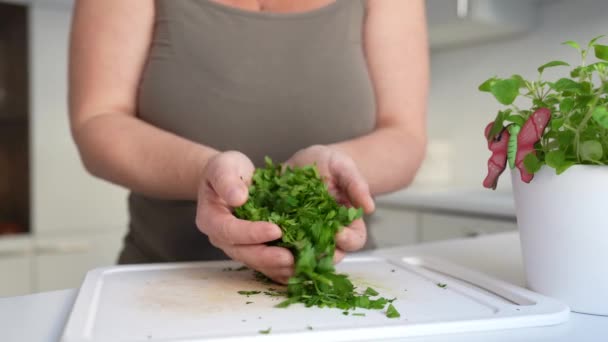 donna taglia professionalmente erbe sul tagliere con coltello da cucina affilato, in cucina casalinga. preparazione spezie, condimenti erbe secche. erba prezzemolo - Filmati, video