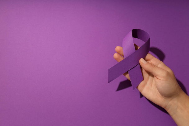 Концепция искоренения насилия в отношении женщин с фиолетовой лентой в руках - Фото, изображение