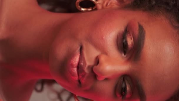 Portret van een jonge vrouw met een afro kapsel en heldere make-up. Ze houdt een rozenbloem in haar hand. Sluiten, Slow Motion. - Video