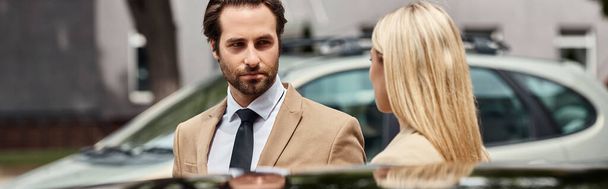barbudo elegante homem de negócios e mulher loira olhando uns para os outros perto do carro na rua, banner - Foto, Imagem