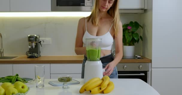Femme sportive fait des épinards verts et smoothie à la banane dans le mélangeur. Images 4k de haute qualité - Séquence, vidéo
