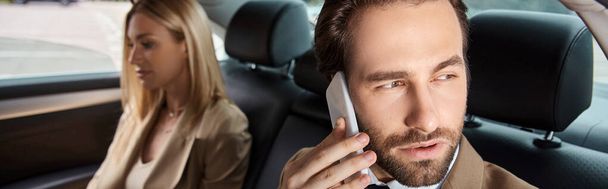 hombre de negocios con estilo en ropa formal hablando en el teléfono inteligente cerca de la mujer rubia en el coche, pancarta - Foto, Imagen