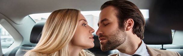 elegante zakenman en aantrekkelijke blonde vrouw zitten oog in oog in luxe auto, banner - Foto, afbeelding