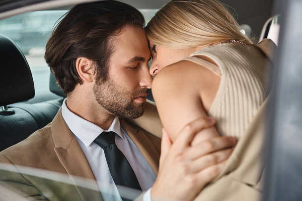 pareja de negocios apasionada y elegante en el desgaste formal abrazar mientras viaja en coche, romance - Foto, imagen