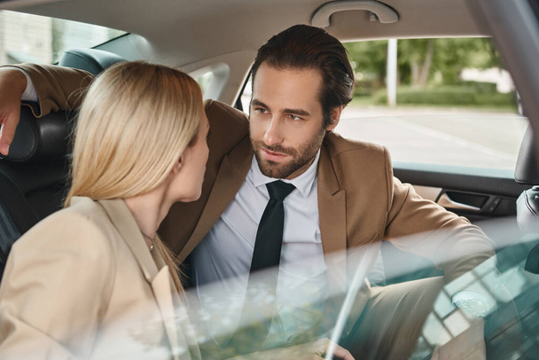 привлекательный бизнесмен смотрит на блондинку коллегу и соблазняет ее во время поездки на машине - Фото, изображение