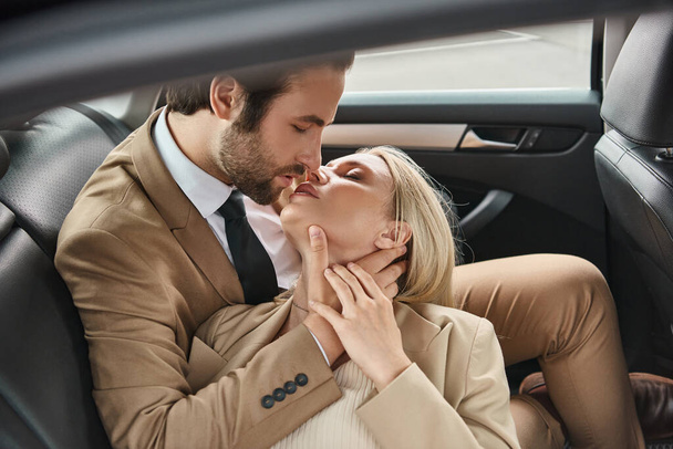 stijlvol en succesvol zakenkoppel zoenen met gesloten ogen tijdens het reizen in de auto, romantiek - Foto, afbeelding