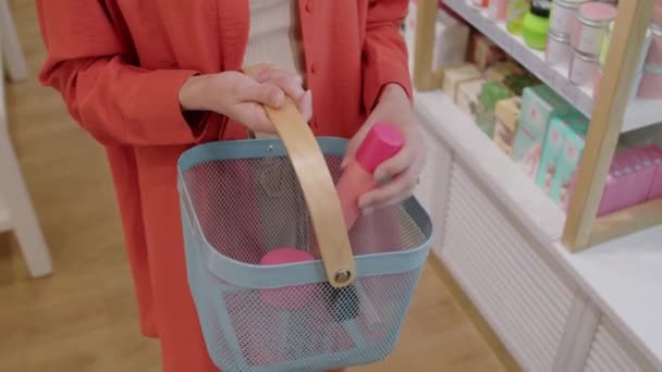 Schnappschuss von Frau, die Deo in Einkaufskorb legt, während sie Kosmetikgeschäft besucht - Filmmaterial, Video
