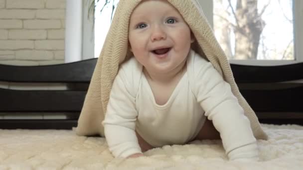 A playful little boy crawls on all fours on the bed with a blanket on his head. Satisfied baby playing on a large bed at home. Slow motion. High quality 4k footage - Footage, Video