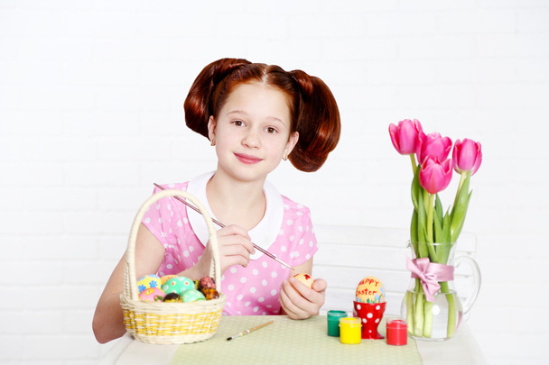 Cute girl decorates Easter eggs, on light background - Fotografie, Obrázek