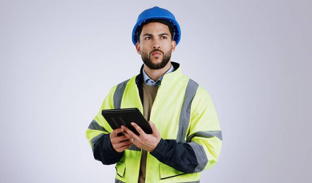 Man, architect and thinking with tablet for construction or planning against a gray studio background. Male person, contractor or engineer in wonder, thought or plan with technology for architecture. - Photo, Image