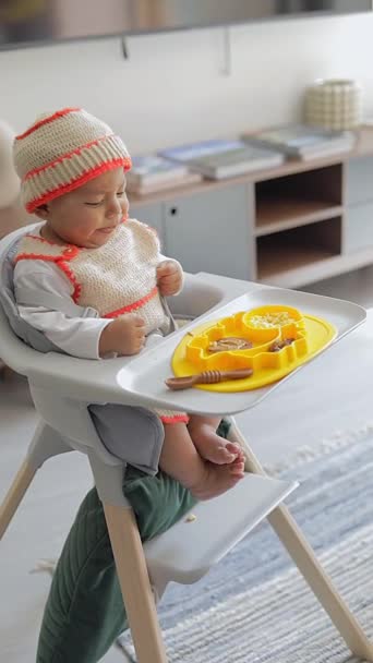 Kiegészítő etetés egy latin csecsemővel, aki a székében ülve, kék tányérral reggelizik.. - Felvétel, videó