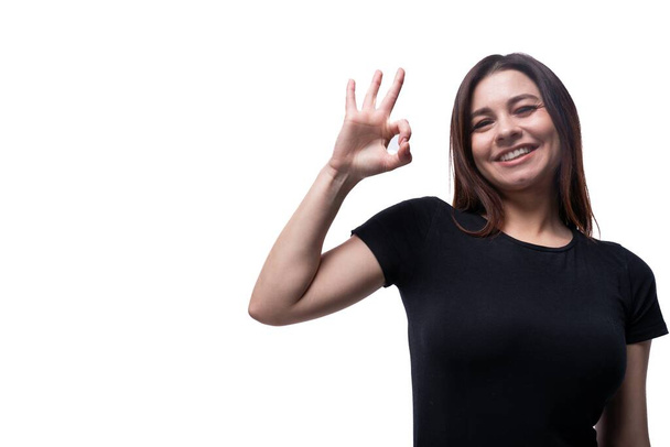Kavkazský roztomilý mladý žena s černými vlasy oblečený v černé tričko gestikulující na bílém pozadí s kopírovacím prostorem. - Fotografie, Obrázek