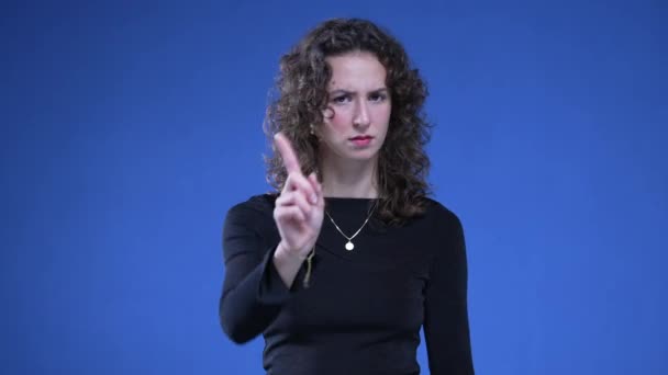 Mulher apontando para câmera expressando "NÃO" agitando o dedo com gesto de desaprovação em pé sobre fundo azul. Pessoa que não gosta abordagem recusar oferta - Filmagem, Vídeo