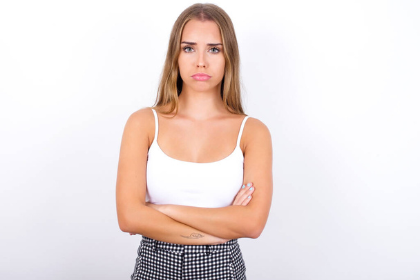 Young Caucasian girl wearing white tank top on white background crying desperate and depressed with tears on his eyes suffering pain and depression. Sad facial expression and emotion concept. - Photo, Image