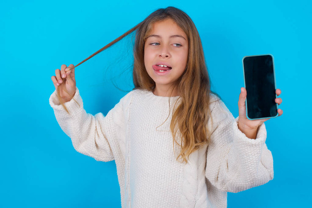 Foto di bella bella bella ragazza adolescente dimostrare schermo del telefono tenere code di capelli - Foto, immagini