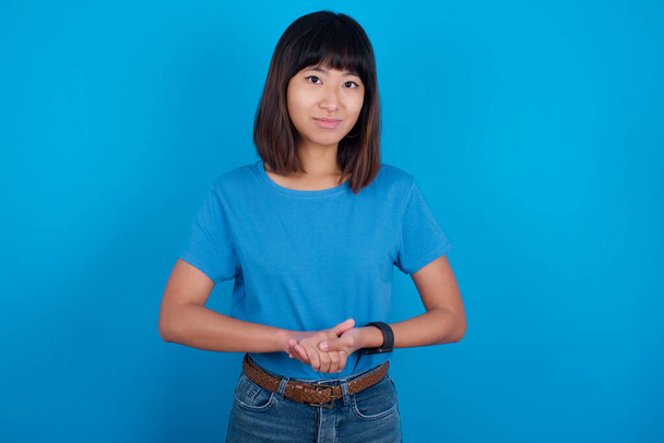 Foto de alegre confiante jovem asiático mulher vestindo azul t-shirt contra azul fundo braços juntos - Foto, Imagem