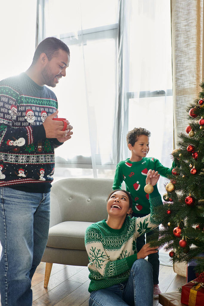 クリスマスツリーを飾る居心地の良い暖かいセーターでジョイスのアフリカ系アメリカ人の家族の垂直ショット - 写真・画像
