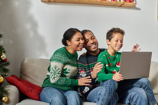 iloinen moderni afrikkalainen amerikkalainen perhe istuu sohvalla yhdessä katsomassa joulun elokuva kannettavalla tietokoneella - Valokuva, kuva