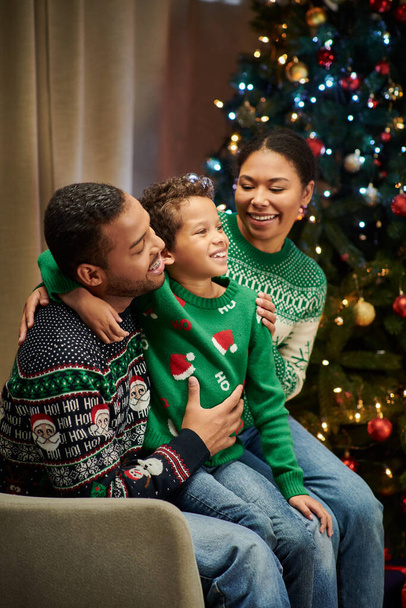 暖かく抱擁し,幸せに笑顔で現代のジョリーアフリカ系アメリカ人の家族の垂直ショット,クリスマス - 写真・画像