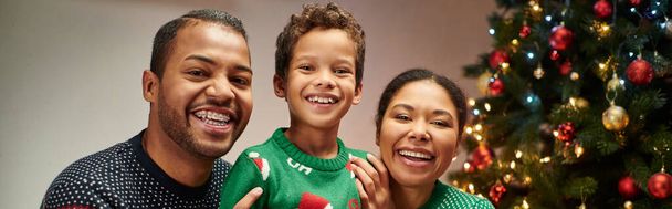 バックドロップ上のクリスマスツリーでカメラで微笑む現代陽気なアフリカ系アメリカ人家族,バナー - 写真・画像
