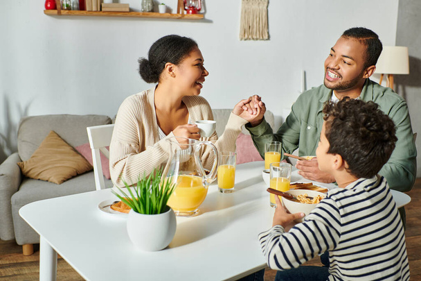楽しいアフリカ系アメリカ人の家族が一緒に朝食を食べ,笑顔でお互いに元気に - 写真・画像