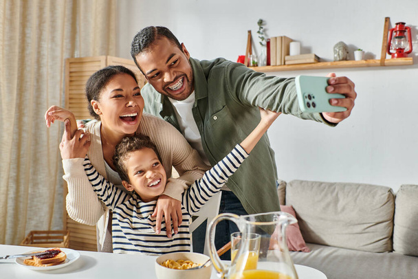 modern vrolijk Afrikaans amerikaanse familie nemen selfies aan tafel ontbijt en glimlachen op de camera - Foto, afbeelding
