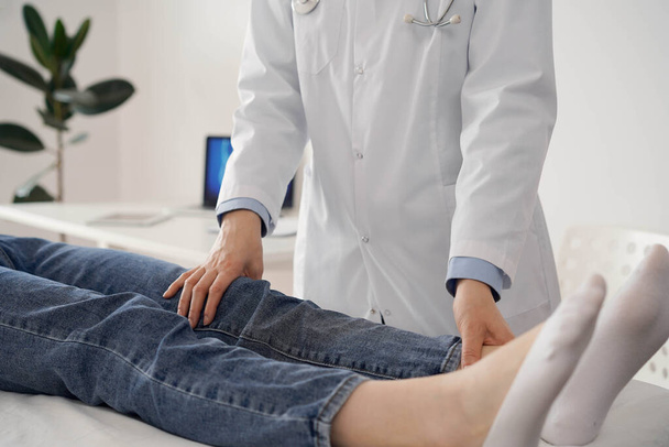 Doctor and patient are at the usual medical inspection in the clinic. Therapist examines a young womans knee. Medicine concept . - Foto, afbeelding