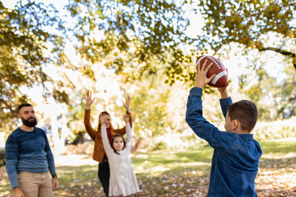 Aile parkta Amerikan futbolu oynuyor. Aile ve çocuklar, doğa konsepti.. - Fotoğraf, Görsel