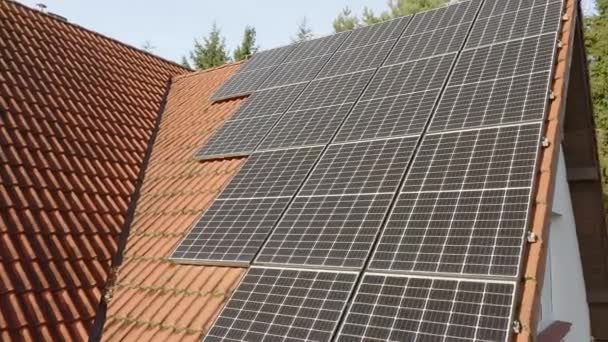 Moderne fotovoltaïsche monokristallijne zonnepanelen van massief siliciumkristal met een verhoogde efficiëntie van het omzetten van zonlicht in elektrische stroom worden geïnstalleerd op het betegelde dak van het huis. - Video
