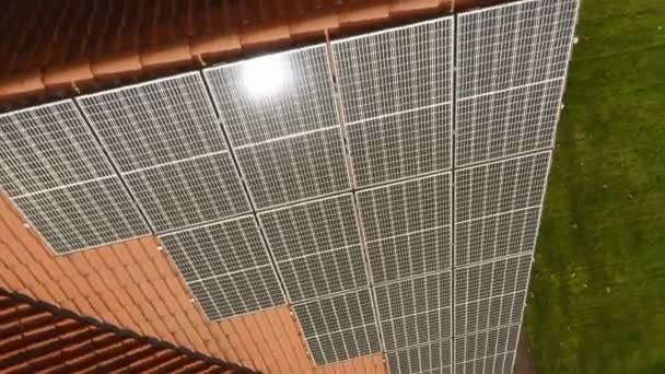 Zonneschijn op fotovoltaïsche monokristallijne zonnemodules gemaakt van één siliciumkristal, met een verhoogde efficiëntie van het omzetten van zonlicht in elektrische stroom op het betegelde dak van het huis. - Video