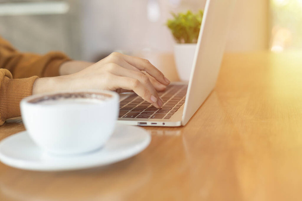 Kobieta ręka pracy i pisania na klawiaturze laptopa na drewnianym stole - Zdjęcie, obraz