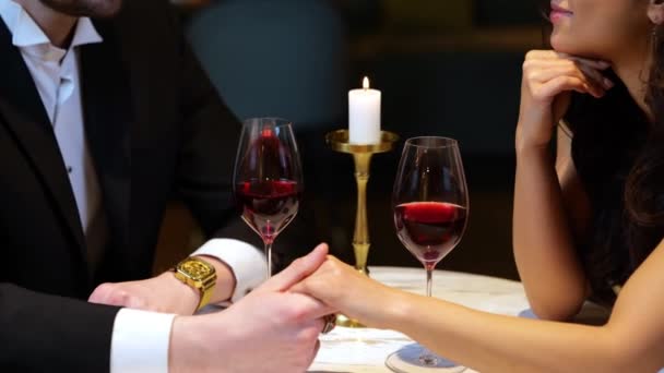 Glücklicher junger Mann und Frau, die sich beim romantischen Abendessen im Restaurant anschauen und Händchen halten. Lebensstil, Liebe, Beziehungskonzept. Echtzeit-Video. - Filmmaterial, Video