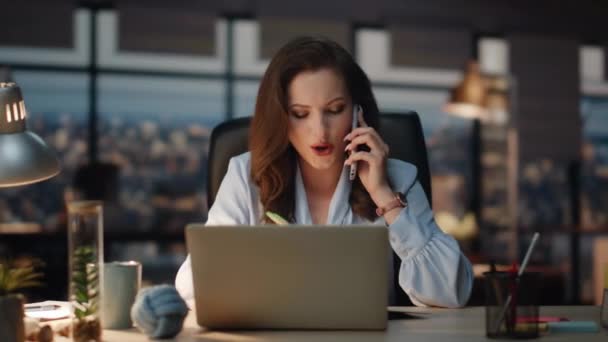 Woman having business call writing notes at office desk. Smiling businesswoman checking information from laptop talking with partner. Friendly lady boss making appointment noting in notebook alone  - Footage, Video