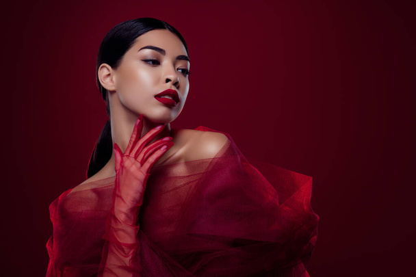 Foto van aziatische jonge vrouw femme fatale touch hals plagen seksueel verlangen schouders uit geïsoleerde donker rode kleur achtergrond. - Foto, afbeelding