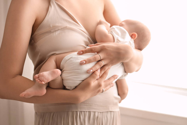 Jeune femme qui allaite son bébé dans la chambre, gros plan
 - Photo, image