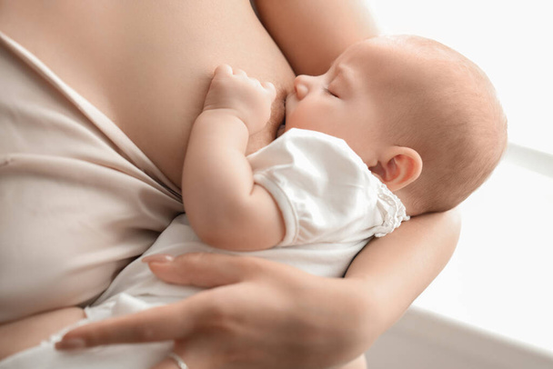 Jonge vrouw borstvoeding haar baby in de slaapkamer, close-up - Foto, afbeelding