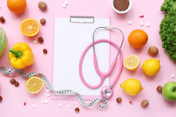 Composizione con appunti, stetoscopio e cibo sano su sfondo rosa - Foto, immagini