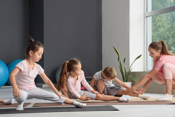 Група маленьких дітей, які практикують йогу з інструктором у спортзалі - Фото, зображення