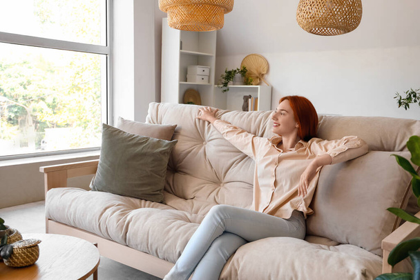 Young woman sitting on couch in living room - Photo, Image