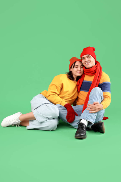feliz jovem casal em roupas quentes sentado no fundo verde - Foto, Imagem